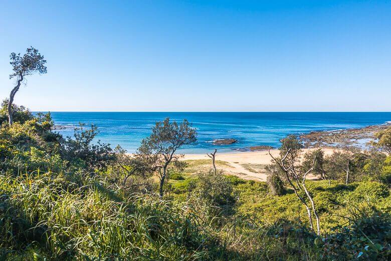 View of Bateau Bay Beach with coastal bushland and rock platforms on the Central Coast