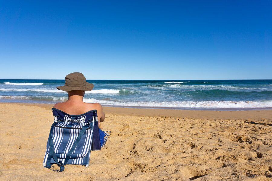 Person relaxing in a beach chair facing the ocean in Australia