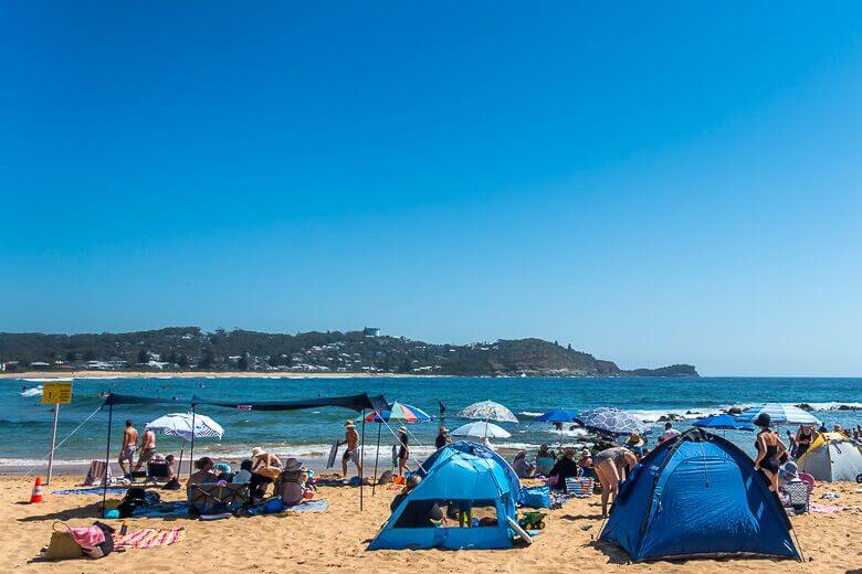 Beach tents set up on a busy Australian beach providing shade for families.