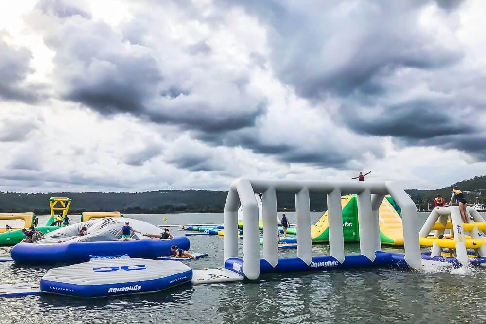 Kids playing on inflatable water obstacles at Central Coast Aqua Park