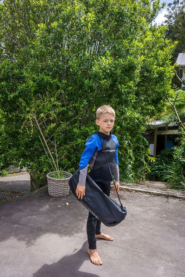 Child wearing a wetsuit carrying a Neso beach tent bag