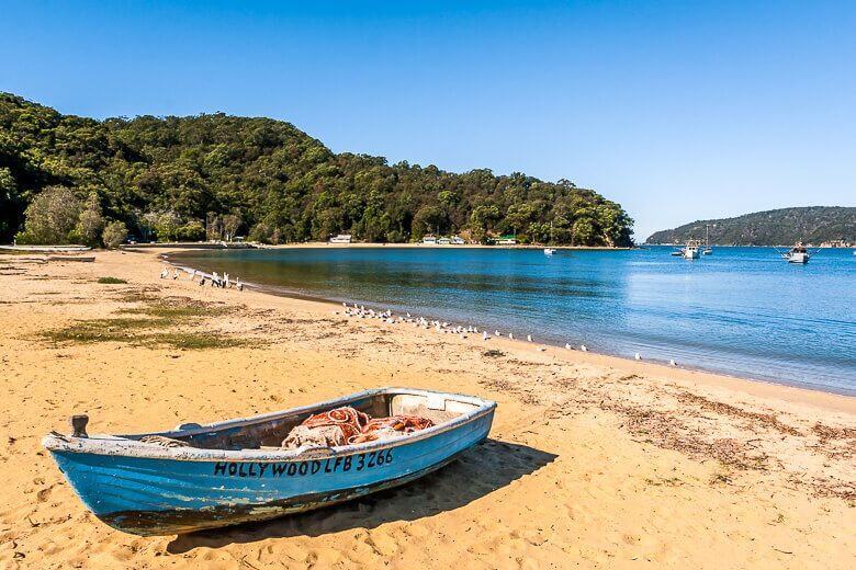 Calm waterfront and sandy shoreline at Patonga Beach with boats on the bay