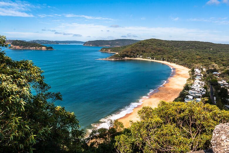 Elevated coastal view of Pearl Beach with curved shoreline and calm blue water