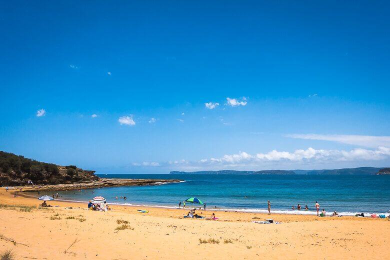 Sandy shoreline and calm ocean at Putty Beach on a clear day