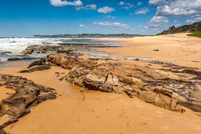 Rocky shoreline and sandy beach at Spoon Bay on the Central Coast