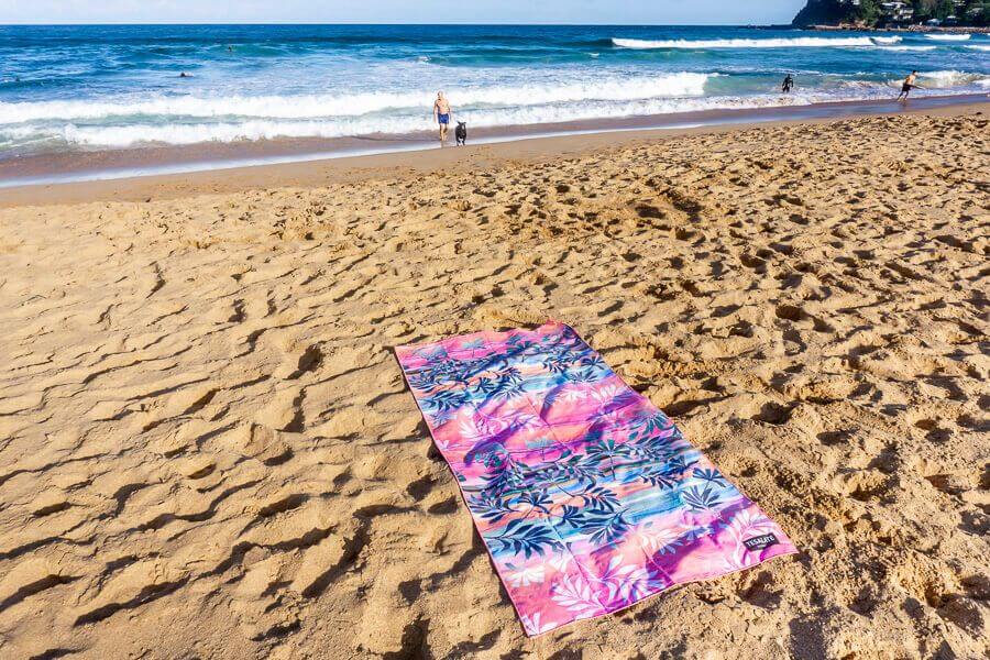 Tesalate beach towel laid out on sandy beach near the ocean