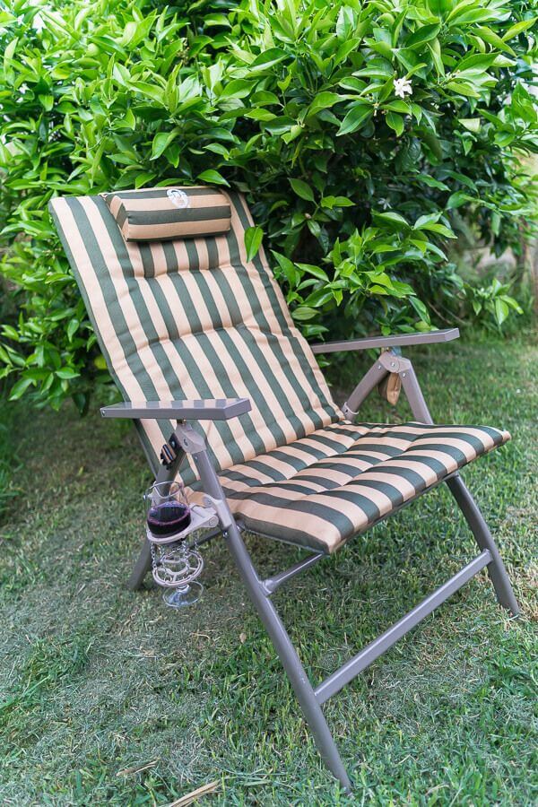 Reclining padded camping chair with armrests set up outdoors