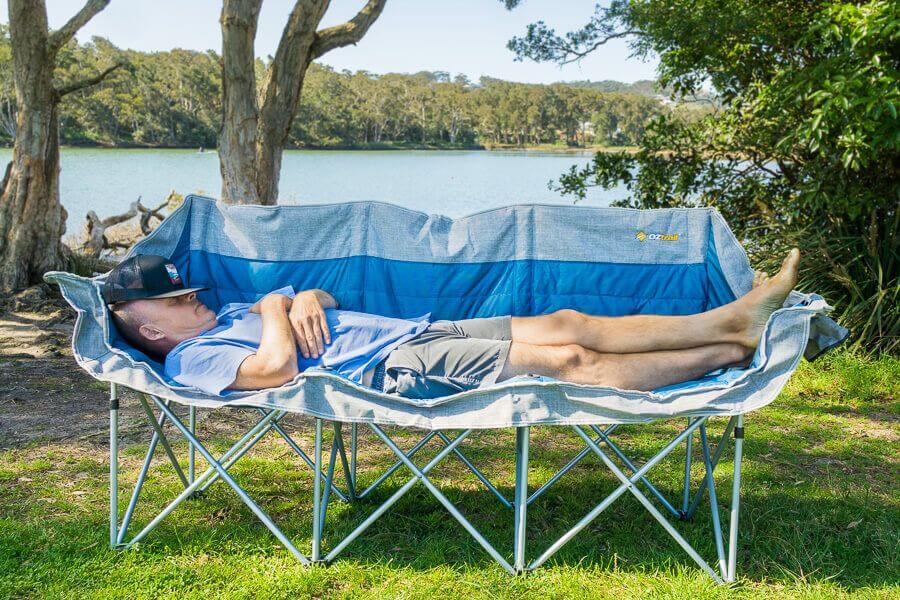 OZtrail Galaxy three seater camping lounge chair set up near water