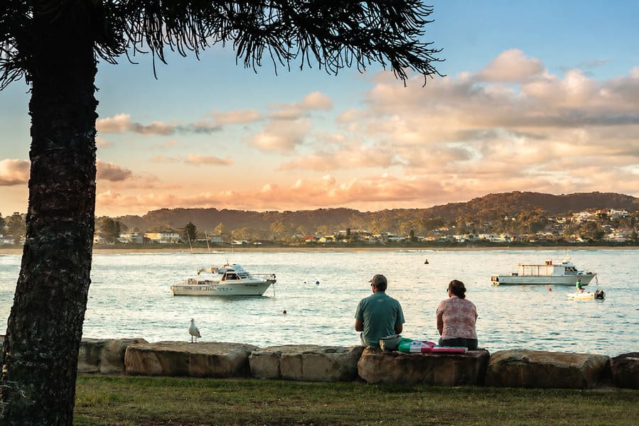 People watching the sunset across Terrigal Haven with boats moored on the water