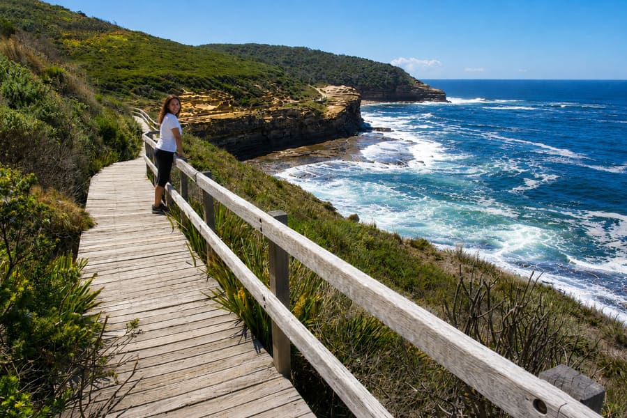Woman walking along the Bouddi Coastal Walk with views over the rocky coastline.