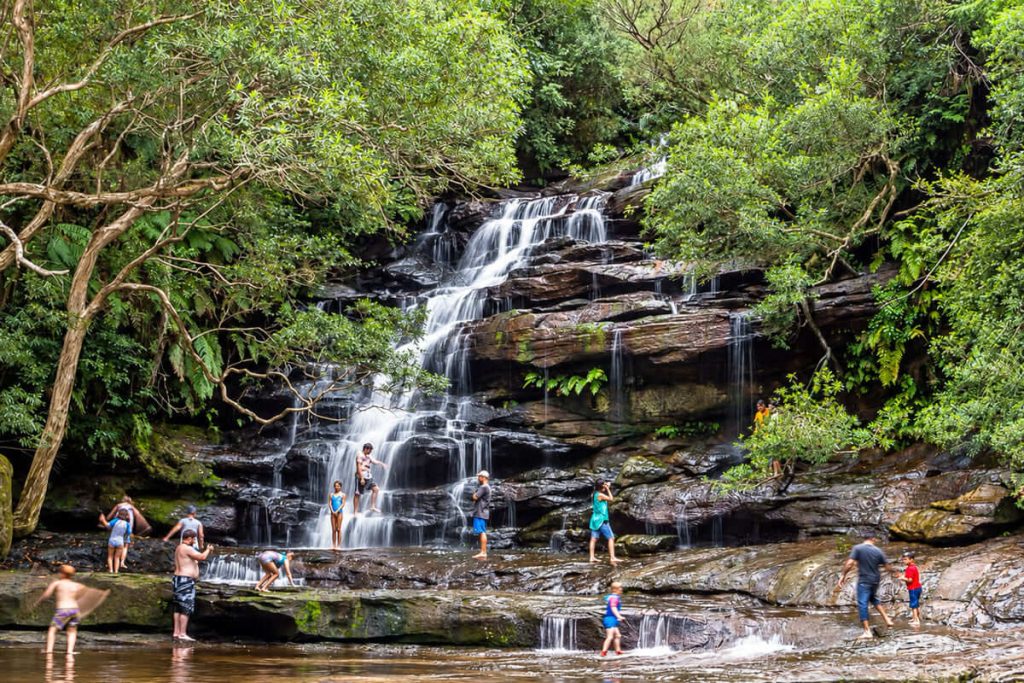 Visitors exploring the cascading waterfall and rock pools at Somersby Falls