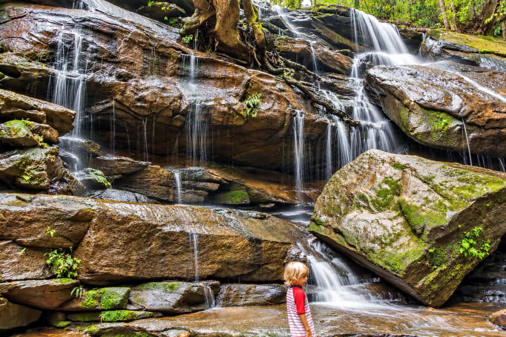 Family standing among the rocks and cascades at Somersby Falls