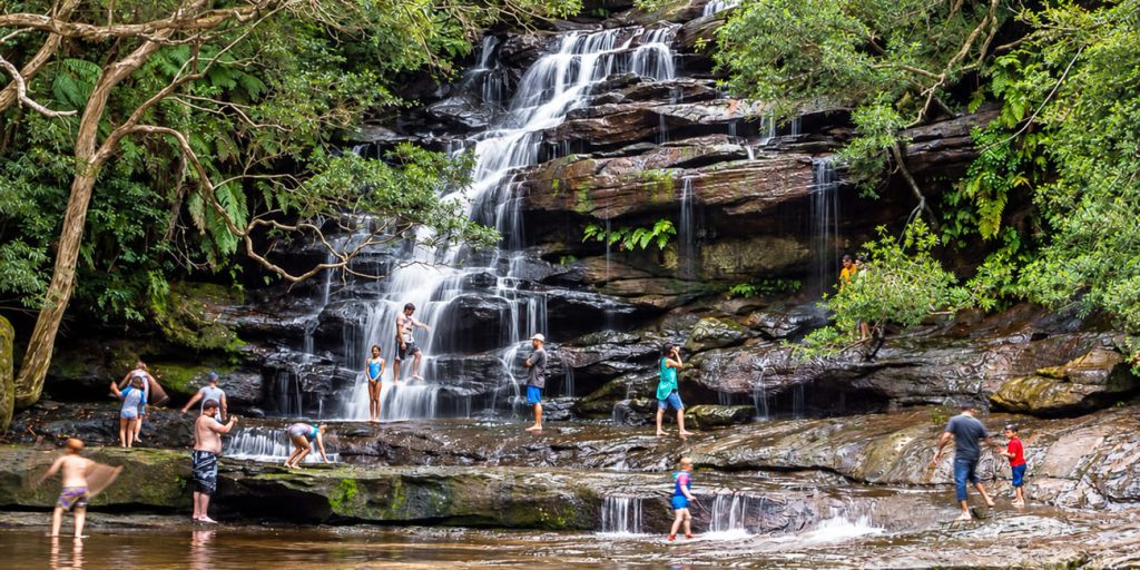 Visitors exploring the cascading waterfall and rock pools at Somersby Falls