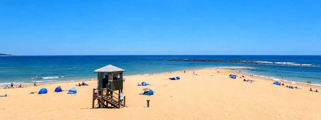 Toowoon Bay Beach with a lifeguard tower, sandy shoreline and calm blue water