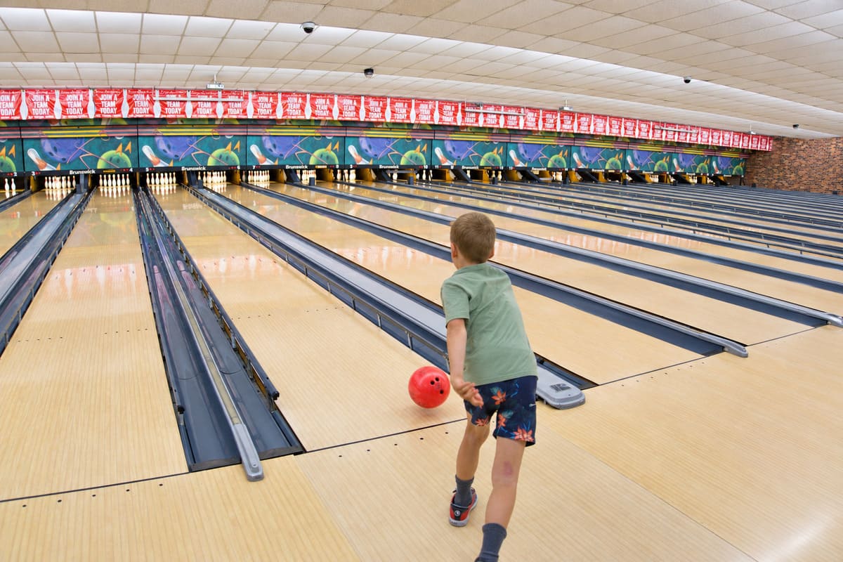 Child bowling with a red ball across the lanes at Bateau Bay Ten Pin Bowl