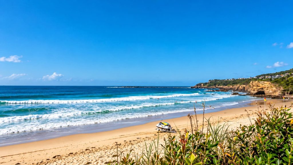 Caves Beach with rolling surf, sandy shoreline, rocky headland and a jet ski on the beach