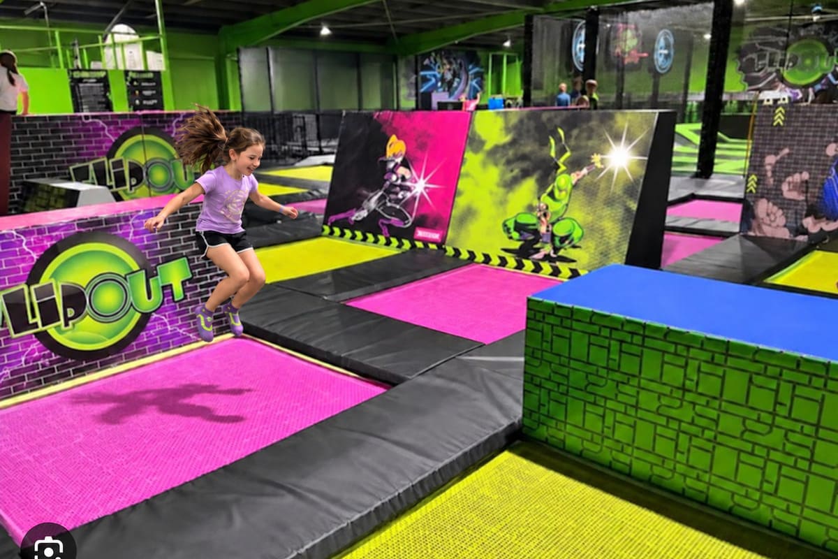 Girl jumping on a bright pink trampoline inside Flip Out indoor trampoline park