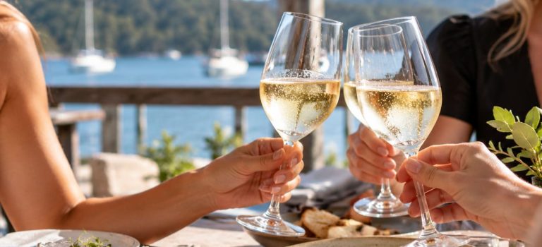 waterfront wine toast three glasses sailboats bay view 768x350
