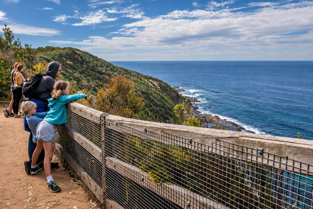 Family stopping at a lookout on the Wyrrabalong Coast Walk with ocean views and rocky coastline