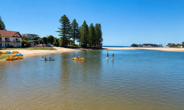 People paddleboarding, kayaking and pedalling on Terrigal Lagoon near Terrigal Beach on the Central Coast of New South Wales.