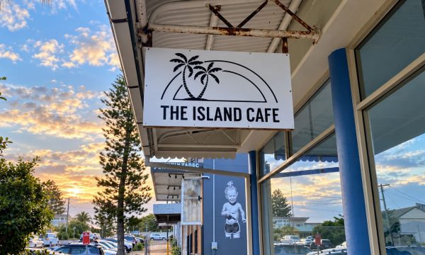 The Island Cafe shopfront sign in Norah Head with sunset light and reflections in the windows